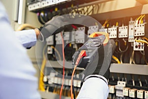 Electrical engineer using digital multi-meter to check current voltage at circuit breaker