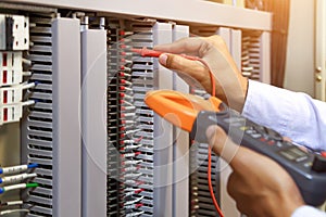 Electrical engineer using digital multi-meter to check current voltage at circuit breaker