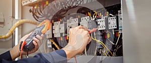 Electrical engineer using measuring equipment to checking electric current voltage at circuit breaker and cable wiring system ,