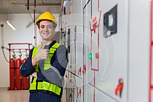 Electrical engineer wear helmet and show thump up near Power Distribution Cabinet in the control room