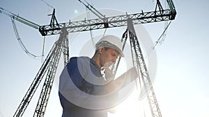 Electrical engineer worker in helmet a working with digital tablet, near tower with electricity. business energy