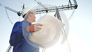 Electrical engineer worker in helmet a working with documents, near tower with electricity. business energy power