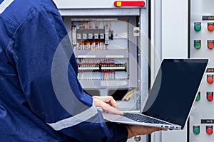 Electrical engineer or Worker working with use laptop near Power Distribution Cabinet in the control room