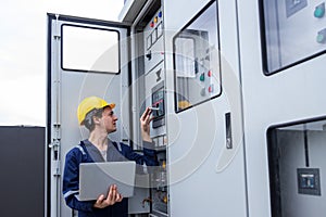 Electrical engineer working in control room. Electrical engineer man checking Power Distribution Cabinet in the control room