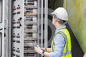 Electrical engineer working in control room. Electrical engineer man checking Power Distribution Cabinet in the control room