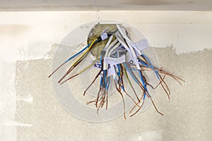 Electrical exposed connected wires protruding from socket on white wall. Electrical wiring installation. Finishing works in