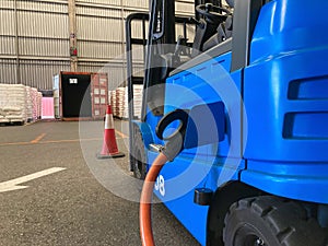 Electrical forklift vehicle park and plug in for charging battery inside of logistic warehouse. Alternative energy source for car