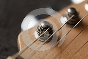 Electrical guitar headstock, machine heads and metal strings closeup. Electric guitar black and white color, detail. Music instrum