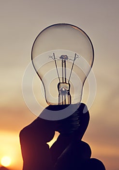 Electrical light bulb in hand.