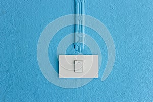 Electrical light switch on blue wall.