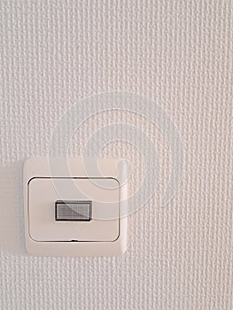 Electrical light switch on white wall with copy space vertical shot