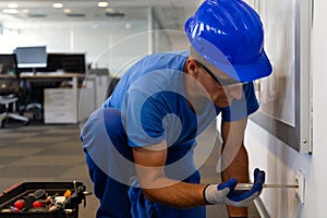 Electrical maintenance inspection.Tehnical maintenance worker checks the electricity in the office premises photo