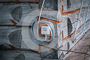 Electrical outlet on the corner of a wooden houseÐ°