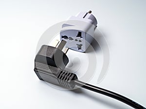 An electrical plug lying next to an adapter for another type of electrical plug.