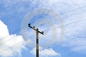 Electrical pole with power lines against hazy blue sky