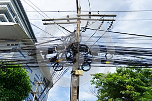 An electrical pole that shows the disorder in the arrangement of the cables.