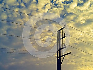 Electrical poles of high voltage transmission lines of 440 volt running on porcelain insulation with cloudy sky background