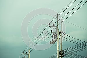 Electrical post by the road with power line cables, transformers and phone lines