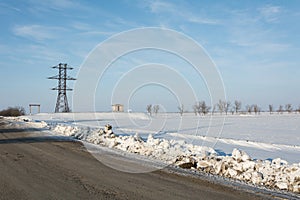 Electrical power line pillar on snow in front of blue sky