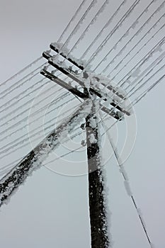 Electrical power lines with hoarfrost on the wooden electric pole on countryside in the winter