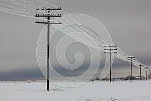 Electrical power lines with hoarfrost on the wooden electric poles on countryside in the winter,