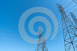electrical power lines producing energy with on electric tower on blue sky background, voltage.
