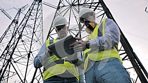 Electrical power pylons and male specialists talking near them