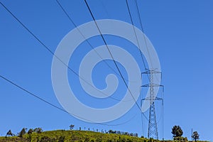 Electrical Powerlines on a Hill before a Blue Sky photo