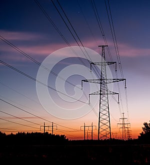 Electrical pylon and high voltage power lines at night.