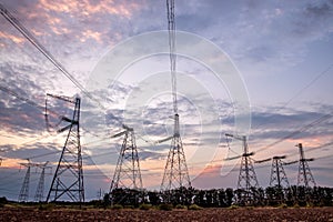 Electrical pylons and high voltage power lines at sunset background. Group silhouette of transmission towers