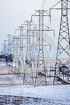 Electrical pylons portrait view with power lines overlooking farm fields in rural Alberta Canada
