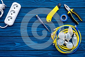 Electrical repair. Bulbs, socket outlet, cabel, screwdriver, pilers on blue wooden background top view copy space
