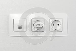 Electrical sockets on the wall with black connection internet plug and white wire. Adapter from the charging device with usb input