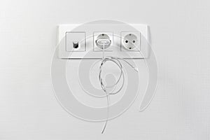 Electrical sockets on the wall with black connection internet plug and white wire. Adapter from the charging device with usb input