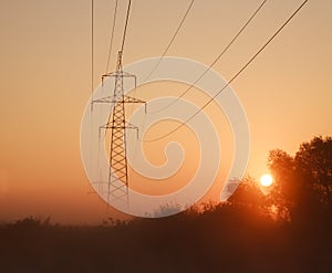 Electrical steel pylon and cable in haze at sunset in forest