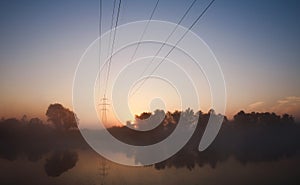 Electrical steel pylon and cable in haze at sunset in forest