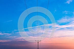 Electrical substation utility pole, state and high voltage power line silhouette with blue cloudy sky at sunset. Purple sunset
