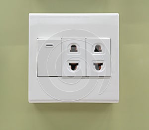 Electrical switch and plug on light green wall