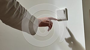 Electrical switch.Saving energy. Reasonable electricity consumption. womans hand turns off the light in the room close