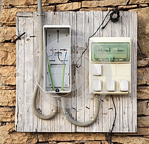 Electrical system with circuit breakers and electrical outlet plugs on a wooden board on a stone wall