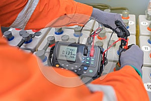 Electrical technician operator is measuring voltage and internal resistance of battery for performance monitoring.