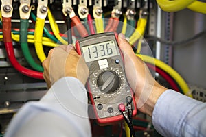 Electrical tester in hands of engineer close-up. Electrician technician at work inspecting cabling connection photo
