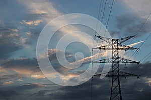 Electrical tower connected to cords under the clouded sky