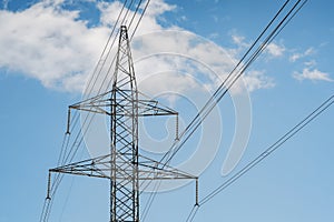 Electrical tower pylon and wires on a blue sky with clouds.