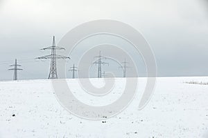 Electrical towers against white sky
