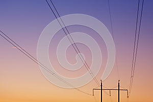 Electrical wires against the dawn sky, in the background two pillars, focusing on the wires, concept