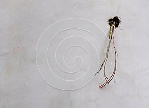 Electrical wires in a dirty white wall