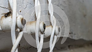 Electrical wiring in vintage style in textile braid on ceramic insulators on a white wooden wall