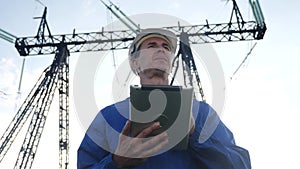 electrical worker engineer in helmet a working with digital tablet, near power tower with electricity. business energy