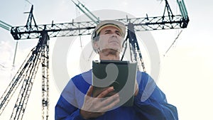 electrical worker engineer in helmet a working with digital tablet power, near tower with electricity. business energy